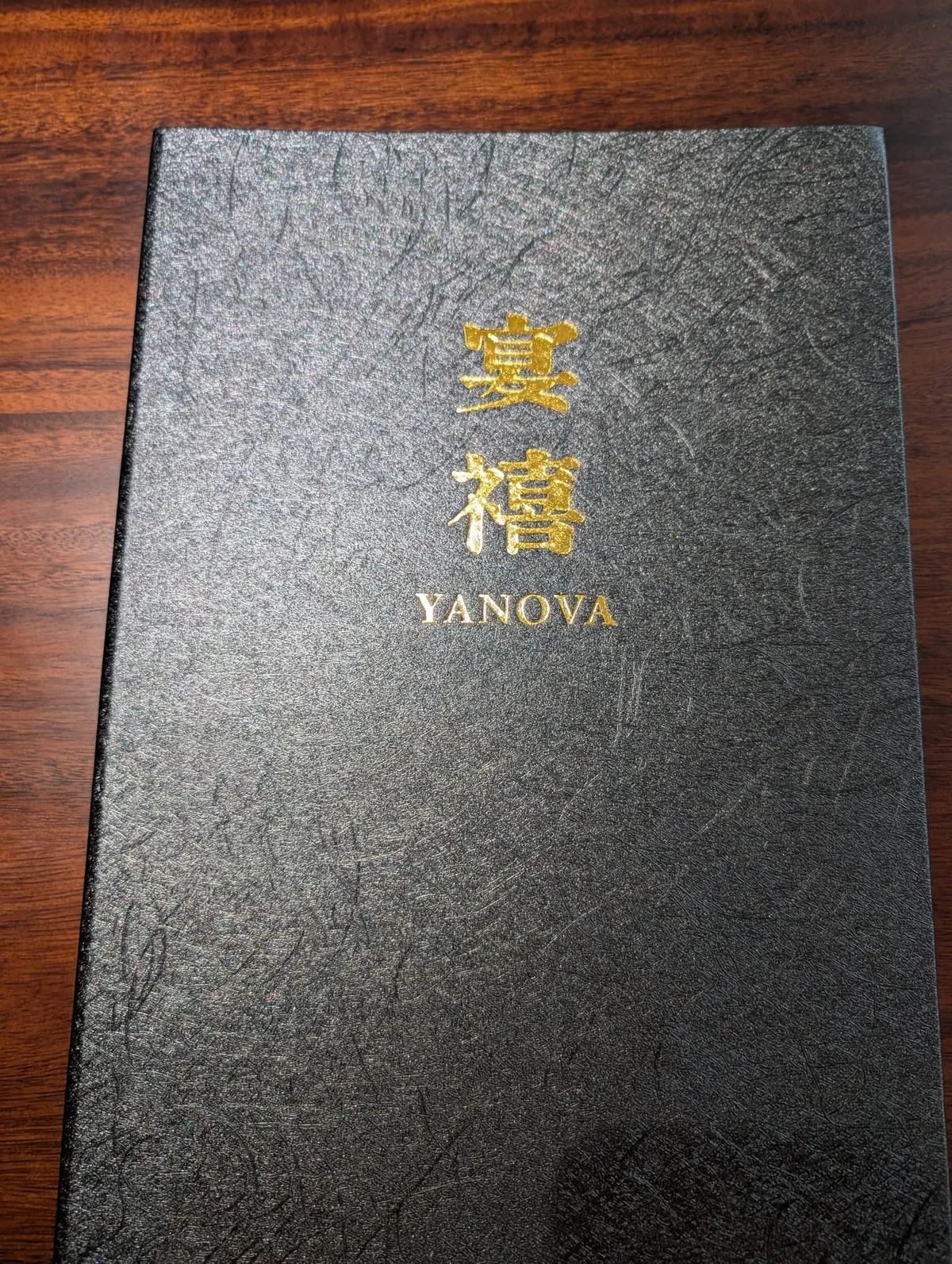 Schwarze Speisekarte des Yanova mit goldener Prägung